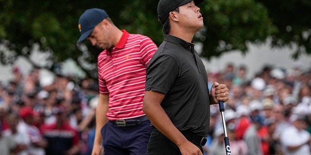 Si Woo Kim, of South Korea, celebrates winning the match against Justin Thomas, right, on the 18th green during their singles match at the Presidents Cup golf tournament at the Quail Hollow Club, Sunday, Sept. 25, 2022, in Charlotte, N.C.