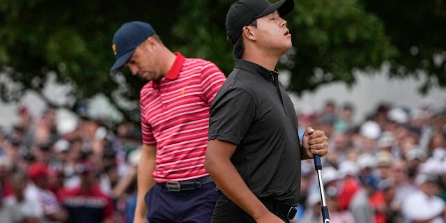 Si Woo Kim, of South Korea, celebrates winning the match against Justin Thomas, right, on the 18th green during their singles match at the Presidents Cup golf tournament at the Quail Hollow Club, Sunday, Sept. 25, 2022, in Charlotte, N.C.