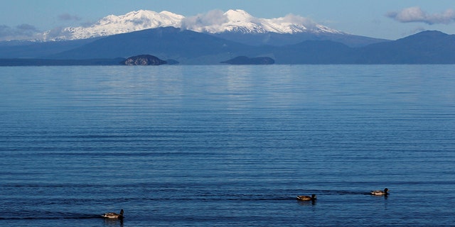 The volcanic peaks of Mounts Tongariro, Ngarruhoe and Ruapehu rise over the shores of Lake Taupo September 28, 2011. 