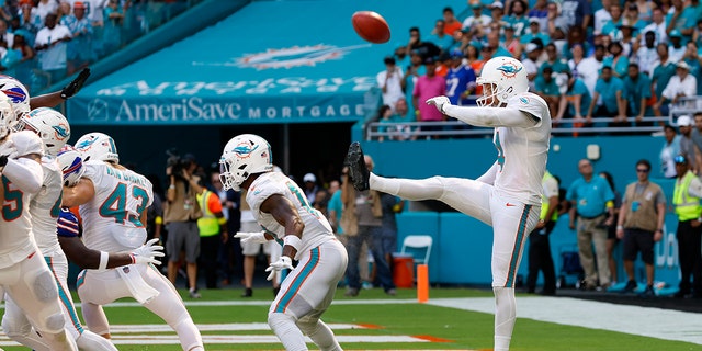 Miami Dolphins punter Thomas Morstead, #4, punts the ball off the backside of Miami Dolphins wide receiver Trent Sherfield, #14, for a safety during the game between the Buffalo Bills and the Miami Dolphins on Sept. 25, 2022 at Hard Rock Stadium in Miami Gardens, Florida.