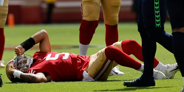 Il quarterback dei San Francisco 49ers Trey Lance giace in campo dopo essere stato affrontato nel primo tempo contro i Seattle Seahawks a Santa Clara, in California, il 18 settembre 2022.