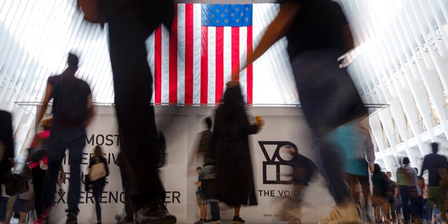 FILE: People walk past an American flag at the start of a work day, at the Oculus, part of the World Trade Center transportation hub in New York, on Sept. 11, 2019.