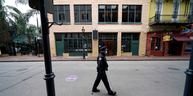A police officer walks down a nearly deserted Bourbon Street during Mardi Gras in the French Quarter of New Orleans, Feb. 16, 2021.