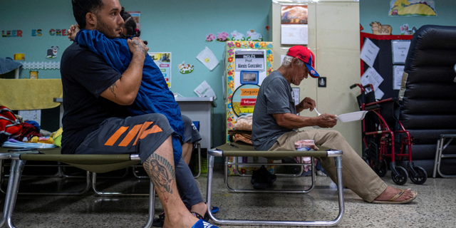 A man who was evacuated from his home embraces a girl in a classroom of a public school turned shelter as Hurricane Fiona and its heavy rains approaches in Guayanilla, Puerto Rico September 18, 2022.