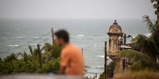 A man stands in front of a beach before the arrival of Tropical Storm Fiona in San Juan, Puerto Rico, Saturday, Sept. 17, 2022. 