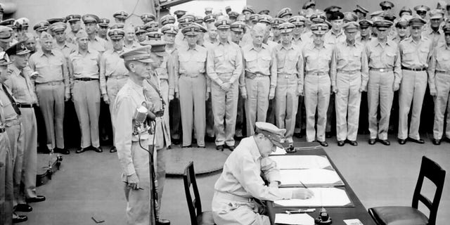 Gen. Douglas MacArthur, seated, signs during formal surrender ceremonies on the USS Missouri in Tokyo Bay, Japan, on Sept. 2, 1945. The Japanese government signed the Instrument of Surrender, ending World War II.