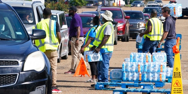 Workers at the Highway 18 Walmart distribute the last of 6,000 cases of water to long line of residents in Jackson, Miss., Thursday, Sept. 1, 2022. A recent flood worsened Jackson's longstanding water system problems. 