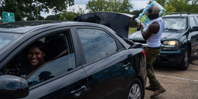 Residents distribute cases of water at Grove Park Community Center in Jackson, Mississippi, on Sept. 3, 2022.