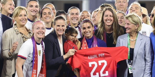 Members of U.S. Soccer, the U.S. Women's National Team Players Association and other dignitaries pose for a photo after signing a collective bargaining agreement providing equal pay for the men's and women's national soccer teams at Audi Field Sept. 6, 2022, in Washington, D.C.