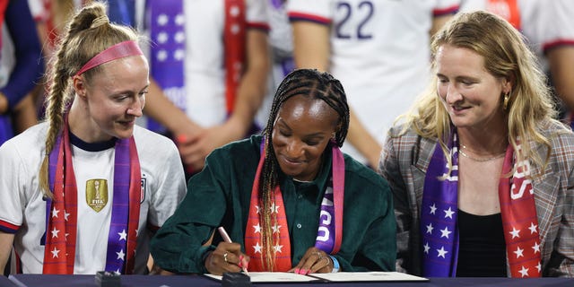 Crystal Dunn, center, signs a collective bargaining agreement providing equal pay for the U.S. men's and women's national soccer teams at Audi Field Sept. 6, 2022 in Washington, D.C.