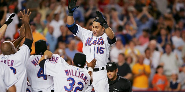 The New York Mets' Carlos Beltran leaps onto home plate in front of cheering teammates after hitting a walk-off, two-run homer in the ninth inning against the St. Louis Cardinals at Shea Stadium. The Mets won, 8-7.
