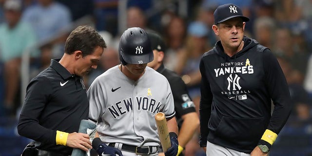 New York Yankees outfielder Andrew Benintendi, center, leaves a game with the help of the Yankees' trainer, left, and Yankees manager Aaron Boone during a a game against the Tampa Bay Rays Sept. 2, 2022, at Tropicana Field in St. Petersburg, Fla.