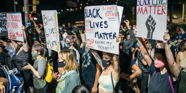 AUSTIN, TX - JULY 26: People hold up signs outside Austin Police Department after a vigil for Garrett Foster on July 26, 2020 in downtown Austin, Texas. Garrett Foster, 28, who was armed and participating in a Black Lives Matter protest, was shot and killed after a chaotic altercation with a motorist who allegedly drove into the crowd. The suspect, who has yet to be identified, was taken into custody.