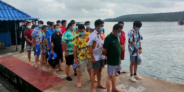 Chinese nationals stand on a pier after being rescued from a sinking ship at an island in Preah Sihanouk Province, southwestern Cambodia, on Sept. 22, 2022. 