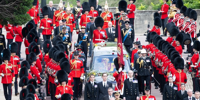 The casket of Queen Elizabeth II, carried in a state hearse as it proceeds toward St. George's Chapel, is followed by King Charles III and other members of the royal family, Sept. 19, 2022, in Windsor, England. 