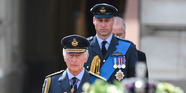 King Charles III and Prince William are seen walking behind the coffin of Queen Elizabeth II during a procession from Buckingham Palace to Westminster Hall.