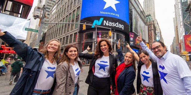 Claudia Romo Edelman, center, along with colleagues, points to the Hispanic Star shout-out by Nasdaq in Lower Manhattan.
