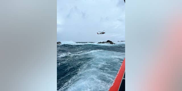 An MH-60T Jayhawk helicopter aircrew deployed a rescue swimmer to secure the fisherman in a harness. 