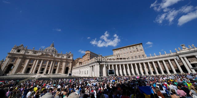 People gather as Pope Francis recites the Angelus from the window of his studio overlooking St.Peter's Square, at the Vatican, Sept. 11, 2022.