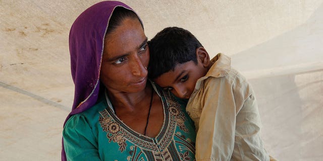 A displaced woman holds son while taking refuge in a camp, following the monsoon season in Sehwan, Pakistan, on Sept. 16, 2022.