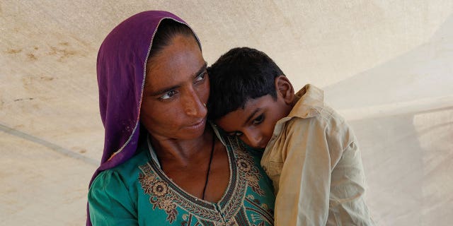 A displaced woman holds son while taking refuge in a camp, following the monsoon season in Sehwan, Pakistan, on Sept. 16, 2022.