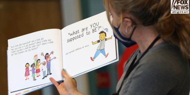 An elementary school teacher is seen reading a book about gender to students.