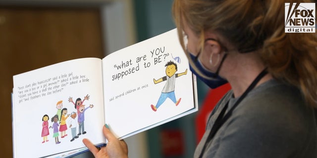 An elementary school teacher is seen reading a book about gender to students.