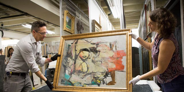 "Woman-Ochre," by painter Willem de Kooning, is getting prepared for an examination by University of Arizona Museum of Art staff Nathan Saxton, left, and Kristen Schmidt in Tucson, Arizona, in August 2017.