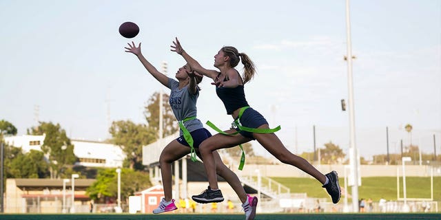 Pictured: Syndel Murillo, 16, left, and Shale Harris, 15, play flag football during team try-outs at the Redondo Union High School on Sept. 1, 2022, in Redondo Beach, California. 