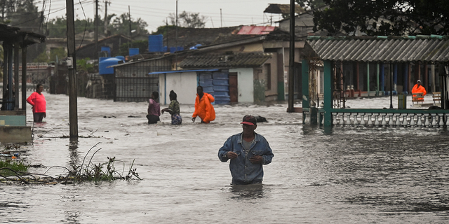 People are seen wading through waist-deep water in Cuba after Hurricane Ian thrashed the western part of the country Tuesday, Sept. 27, 2022.