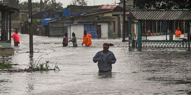 People are seen wading through waist-deep water in Cuba after Hurricane Ian thrashed the western part of the country Tuesday, Sept. 27, 2022.