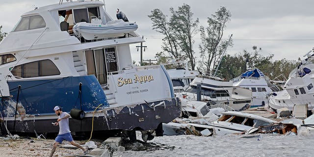Joe Dalton, on vacation from Cleveland, Ohio, checks out beached boats at Ft. Myers Wharf along the Caloosahatchee River, on Thursday, Sept. 29, 2022, in Fort Myers, Florida, following Hurricane Ian. 