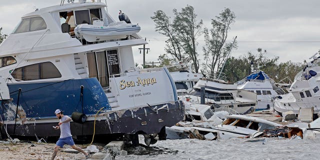 Joe Dalton, on vacation from Cleveland, Ohio, checks out beached boats at Ft. Myers Wharf along the Caloosahatchee River, on Thursday, Sept. 29, 2022, in Fort Myers, Florida, following Hurricane Ian.