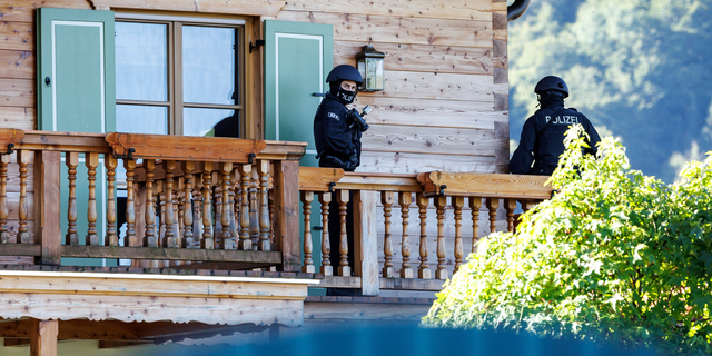 Masked police officers stand on a balcony of a house belonging to Russian oligarch Usmanov during a raid in Rottach-Egern, Germany, Wednesday, Sept.21, 2022.