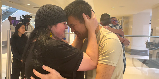 Andy Huynh, left, and Alex Drueke, far right, are seen hugging their loved ones after arriving at Birmingham-Shuttlesworth International Airport in Birmingham, Ala., Saturday, Sept. 24, 2022. The U.S. military veterans disappeared three months ago while fighting Russia with Ukrainian forces. They were released earlier this week by Russian-backed separatists as part of a prisoner exchange.