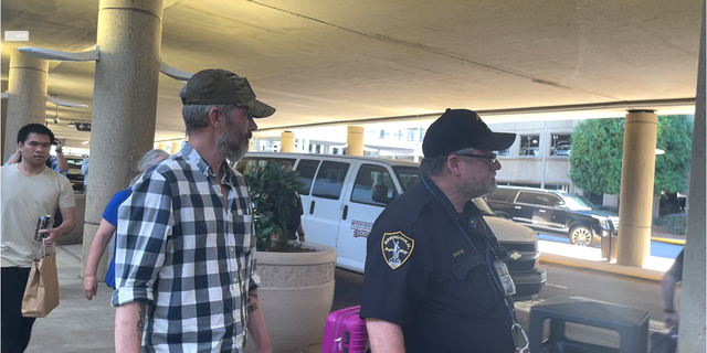 Andy Huynh, far left, and Alex Drueke, right, are seen leaving Birmingham-Shuttlesworth International Airport in Birmingham, Ala., Saturday, Sept. 24, 2022. The U.S. military veterans disappeared three months ago while fighting Russia with Ukrainian forces. They were released earlier this week by Russian-backed separatists as part of a prisoner exchange.