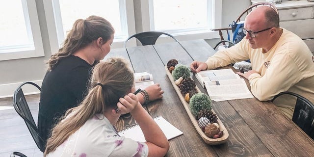 Alan Gaddy teaches his daughters a history lesson at the kitchen table.