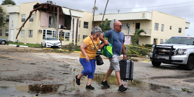 King Point resident Maria Esturilho is escorted by her son, Tony Esturilho, as they leave behind the damage from an apparent overnight tornado spawned from Hurricane Ian at Kings Point 55+ community in Delray Beach, Fla., on Wednesday, Sept. 28, 2022.  