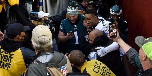 Jalen Harts of the Philadelphia Eagles celebrates with fans who fell to the ground after a railing collapsed following their 20-16 win over the Washington football team at FedEx Field on January 2, 2022 in Landover, MD.