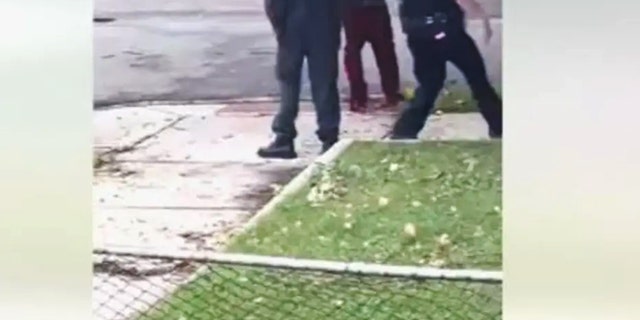 Screenshot of video of irate barefoot man with baby ranting at police. 