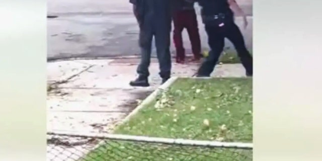 Screenshot of video of irate barefoot man with baby ranting at police. 