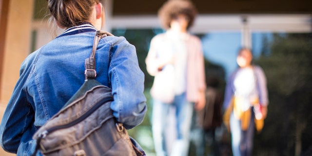 Young student walks alone onto school campus.
