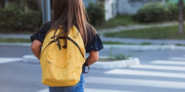 Kid wearing school bag when crossing the street on her way to school