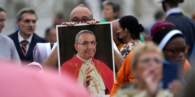 A man holds a photo of Pope John Paul I during the beatification ceremony led by Pope Francis in St. Peter's Square at the Vatican. 