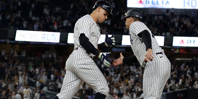 Aaron Judge #99 of the New York Yankees shakes hands with first base coach Travis Chapman #75 as he rounds the bases after hitting his 60th home run of the season during the 9th inning of the game against the Pittsburgh Pirates at Yankee Stadium on September 20, 2022 in the Bronx borough of New York City.