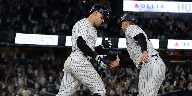 New York Yankees'ten 99 numaralı Aaron Judge, 20 Eylül'de Yankee Stadyumu'nda Pittsburgh Pirates'e karşı oynanan maçın 9. devresinde sezonun 60. ev koşusunu yaptıktan sonra üsleri turlarken birinci kale antrenörü Travis Chapman #75 ile el sıkışıyor. , 2022, New York şehrinin Bronx ilçesinde.