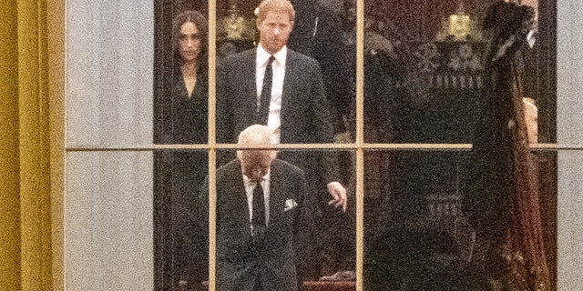 King Charles III stands inside Buckingham Palace with Prince Harry and Meghan Markle as the royal family awaits Queen Elizabeth II's casket.