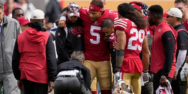 El mariscal de campo de los 49ers de San Francisco, Trey Lance (5), recibe ayuda para subirse a una plataforma rodante durante la primera mitad de un partido de fútbol americano de la NFL contra los Seattle Seahawks en Santa Clara, California, el domingo 18 de septiembre de 2022.