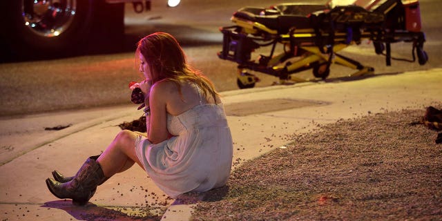 A woman sits on a curb on Oct. 2, 2017, at the scene of the Las Vegas concert shooting that killed 58 people and injured hundreds on Oct. 1, 2017.