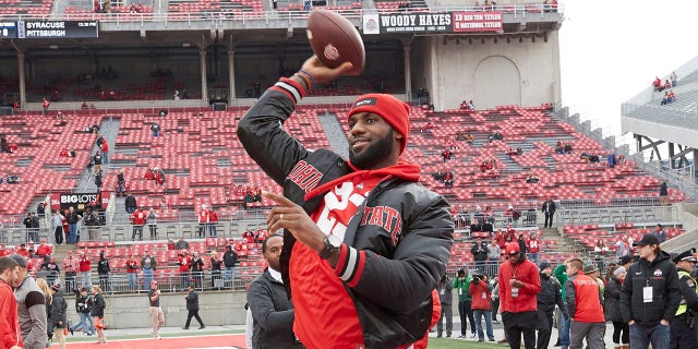 Cleveland Cavalier LeBron James passes on the field with teammate J.R. Smith before an Ohio State-Michigan game at Ohio Stadium in Columbus, Ohio, Nov. 26, 2016.